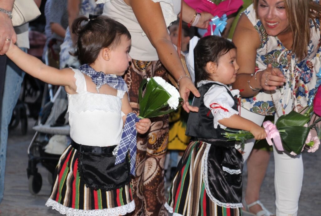 -Dos niñas vestidas de manchega llevan su ofrenda floral a la Virgen de Peñarroya